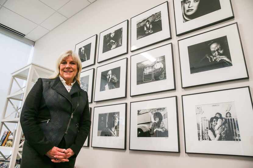 Paige Flink poses next to a wall of photographs of former Family Place clients photographed...