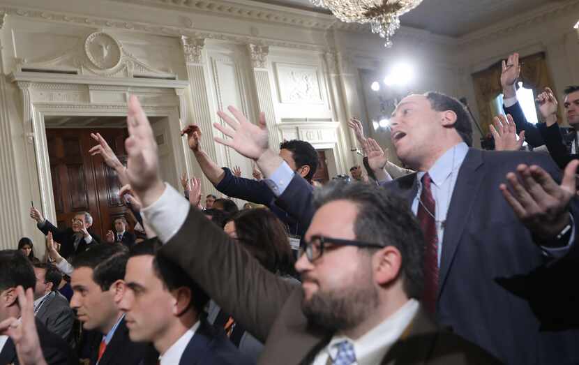 Reporters attempt to pose questions to at President Trump's news conference announcing...