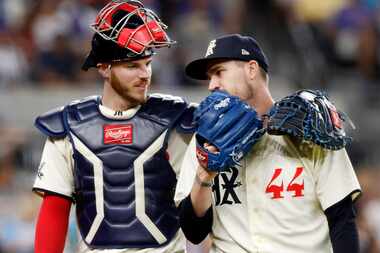Texas Rangers starting pitcher Andrew Heaney (44) leans into to talk to catcher Jonah Heim...