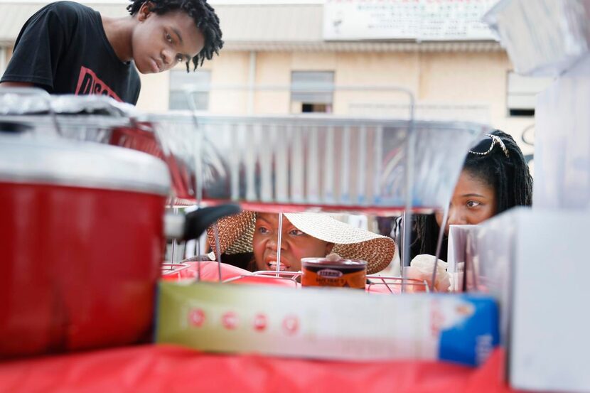 
Shanay Wise (center) sets a warming fire for the food at her Collard Green Cultural...