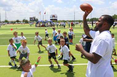 Dallas Cowboys linebacker Micah Parsons looks to throw the ball as he interacts with young...