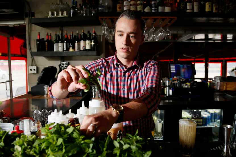 Kyle Hilla, a bar manager at Bolsa restaurant in Dallas, picks a herb piece while he mixes a...