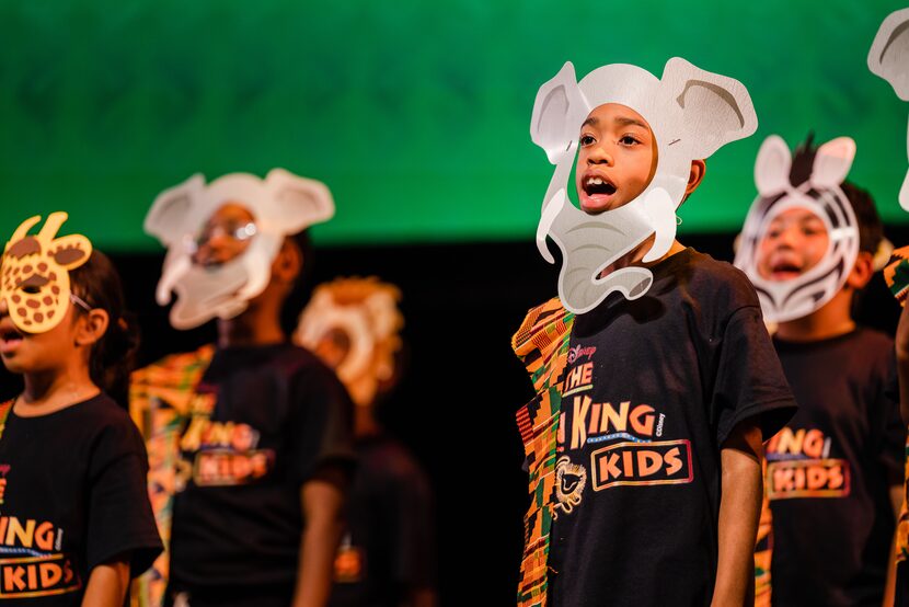 Kids in elephant masks perform onstage.