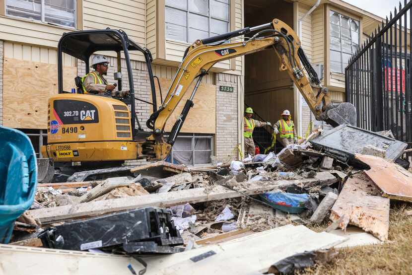 Workers remove debris from the apartment complex on Thursday, Sept. 30, 2021.