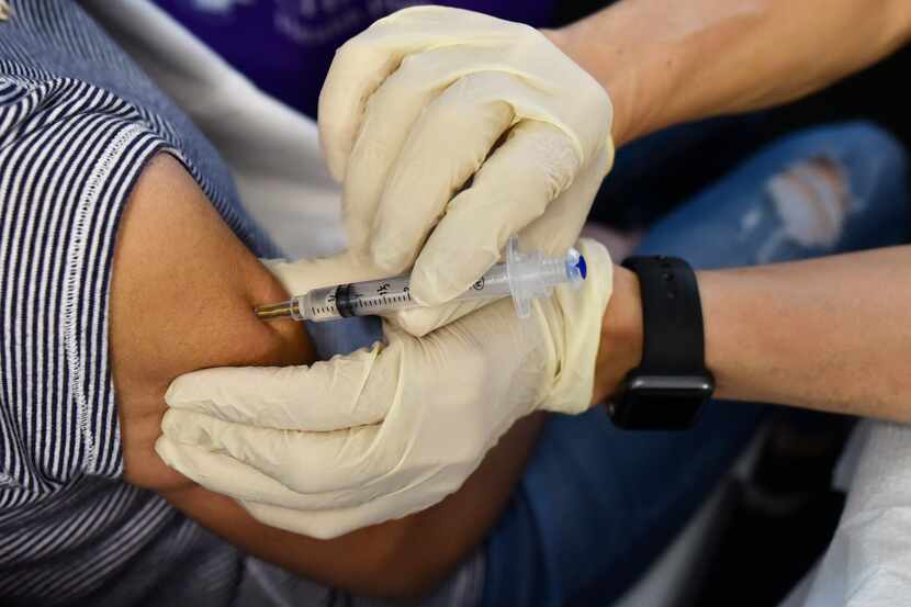 Dr. Philip Huang, Dallas County's health director, distributes a flu vaccine during a health...