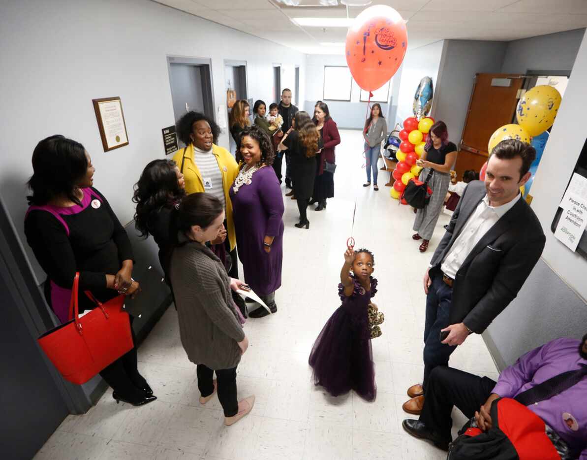 Alona Curry, 3, plays with a balloon after being adopted by Debra Curry (in purple) during...