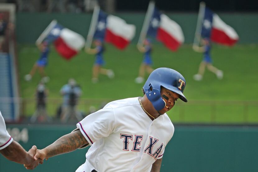 Texas Rangers left fielder Willie Calhoun (55) is congratulated as he rounds third base...