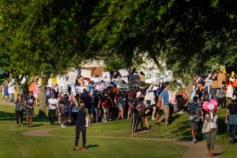 Demonstrators march around the perimeter of Berkner Park during a protest organized by...