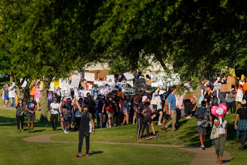 Demonstrators march around the perimeter of Berkner Park during a protest organized by...