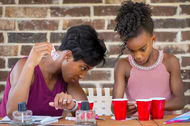 Claudia Coleman watches her daughter Brooklyn, 9, work on a project that is part of the Girl...