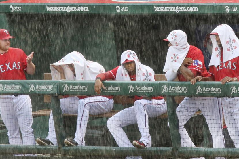 Texas relief pitcher Robbie Ross, left, endures the downpour as teammates Matt Garza, Engel...