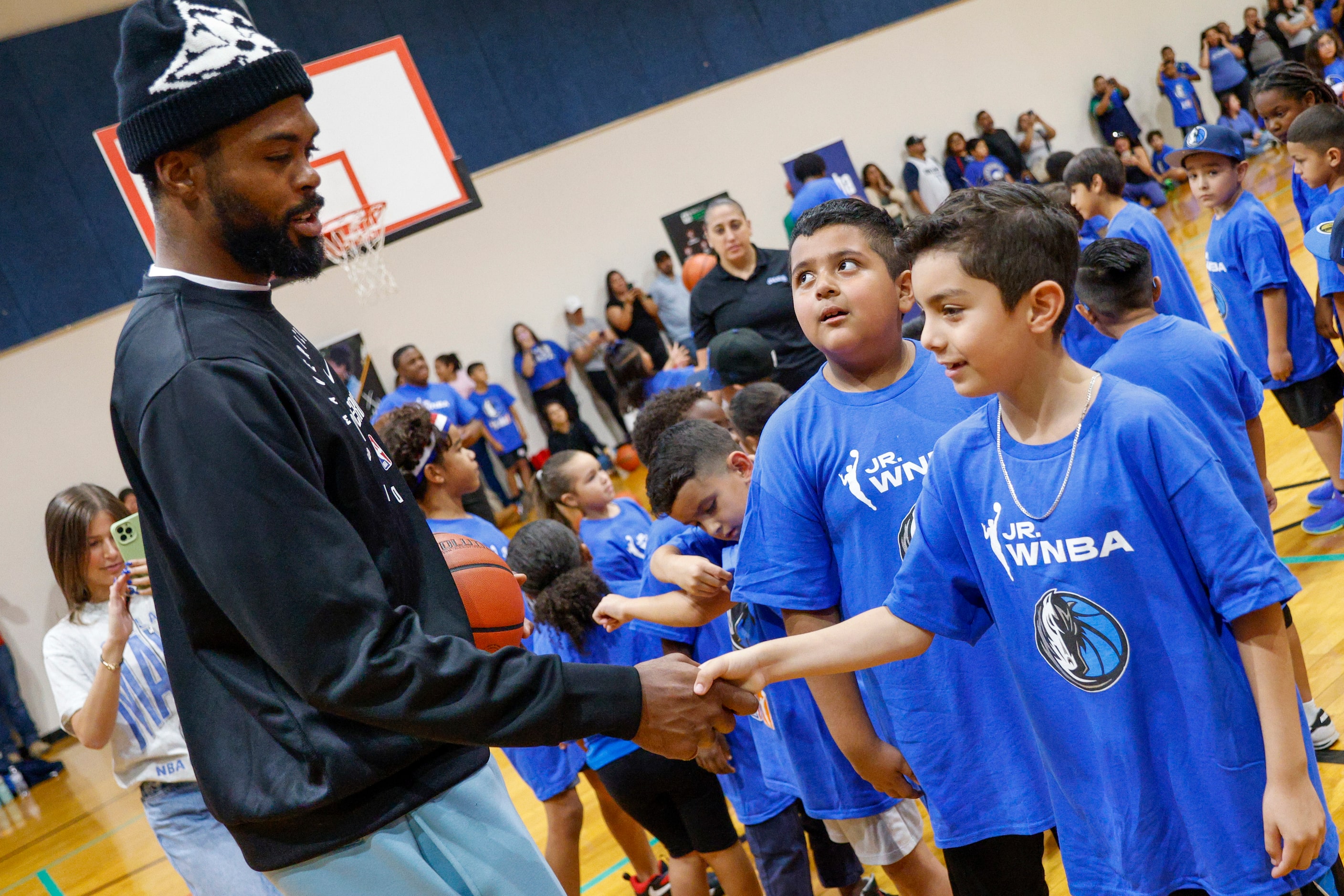 Dallas Mavericks forward Naji Marshall shakes hands with children during a basketball...