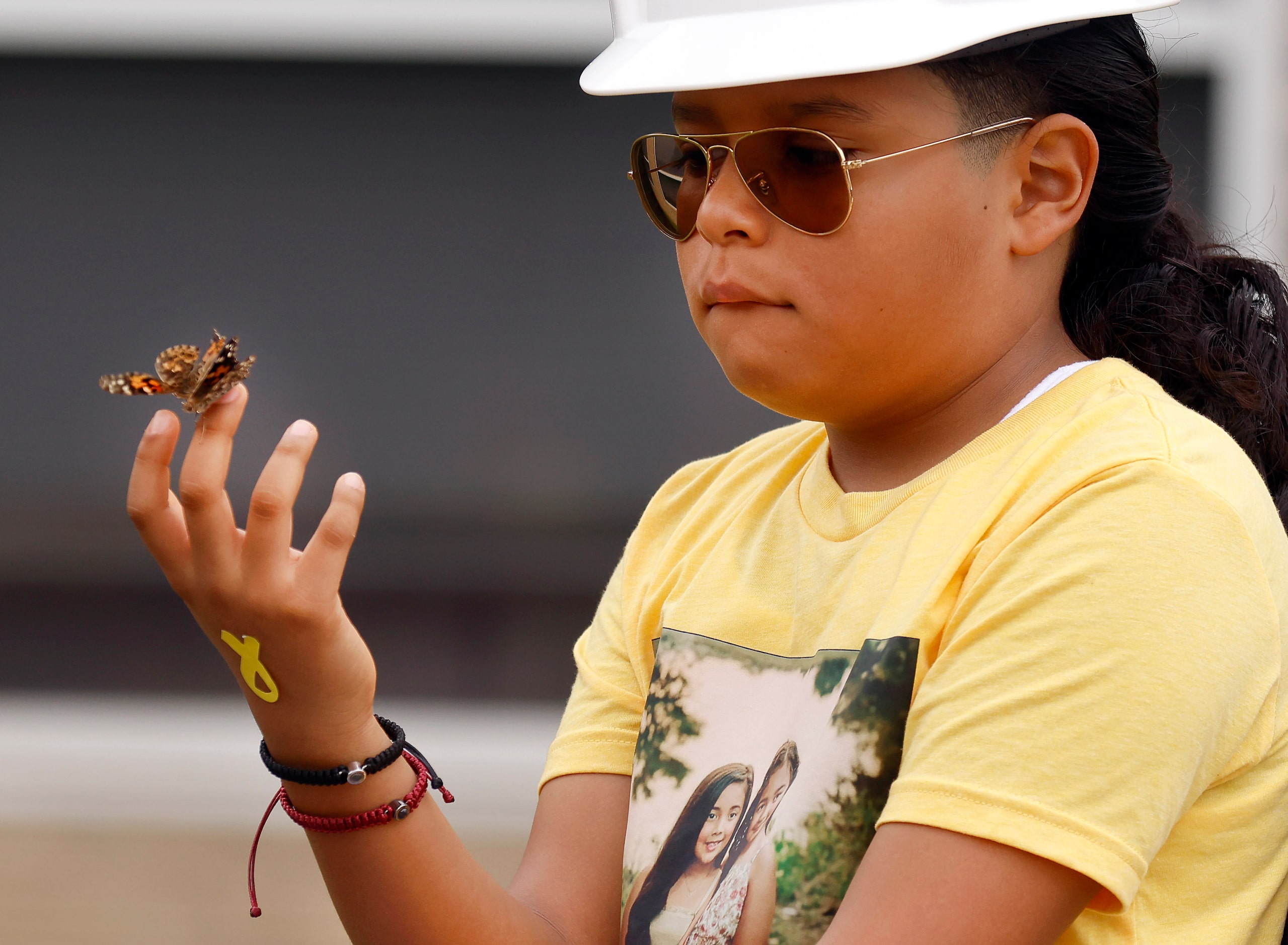 Wearing a shirt of Daniela and Sofia Mendoza, third grader Jeremiah Ramos holds butterflies...