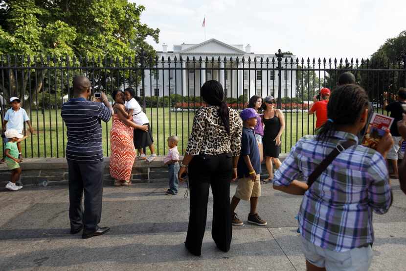 Tourists take pictures of the White House as debt talks continue in Washington, on July 24,...