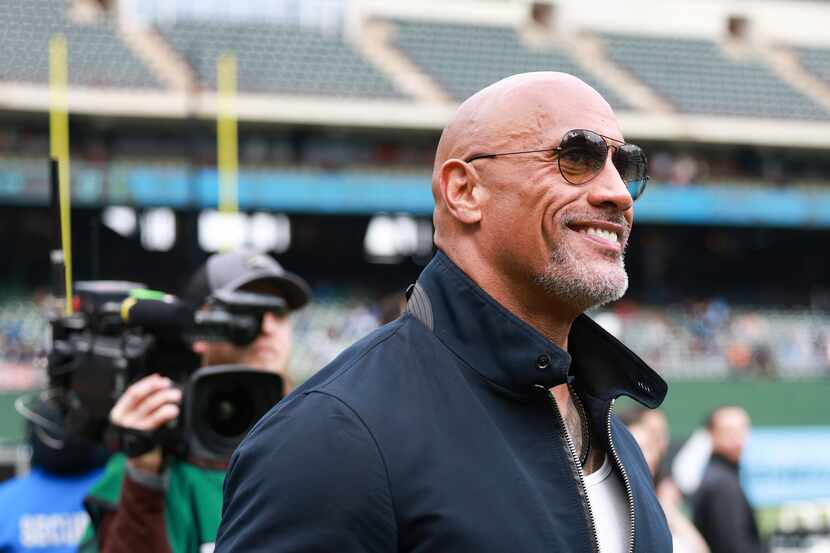 Dwayne “The Rock” Johnson walks on the field’s sidelines before an XFL football game between...