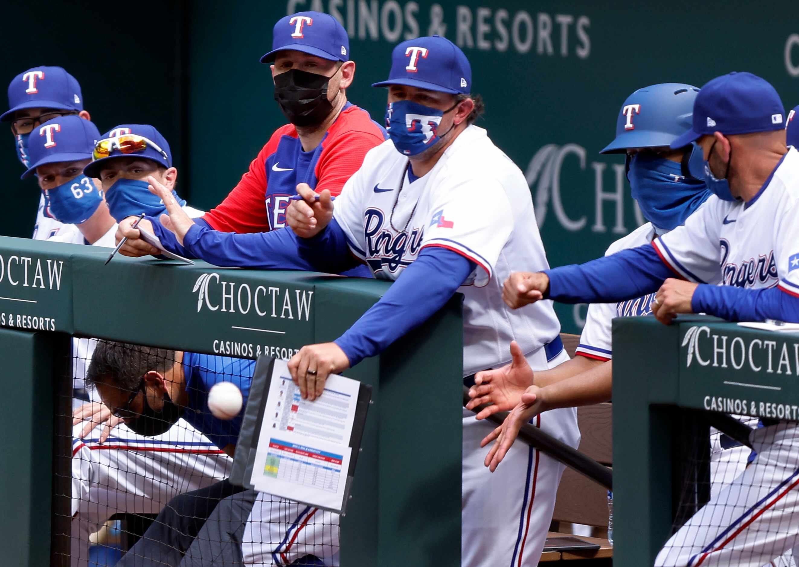 A Texas Rangers coach deflects a foul ball off his clip board during their Opening Day game...
