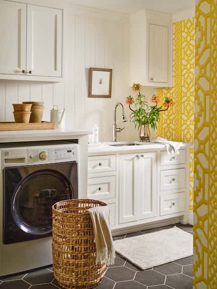 Vertical-printed wallpaper and thoughtfully-placed cabinetry creates the illusion of a...
