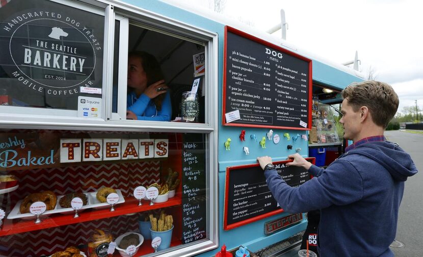 
Ben Ford, right, co-owner of the Seattle Barkery, adjusts menus for dogs and humans while...