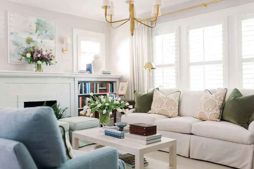 Living room with a white couch and throw pillows, large window with white drapes, and...