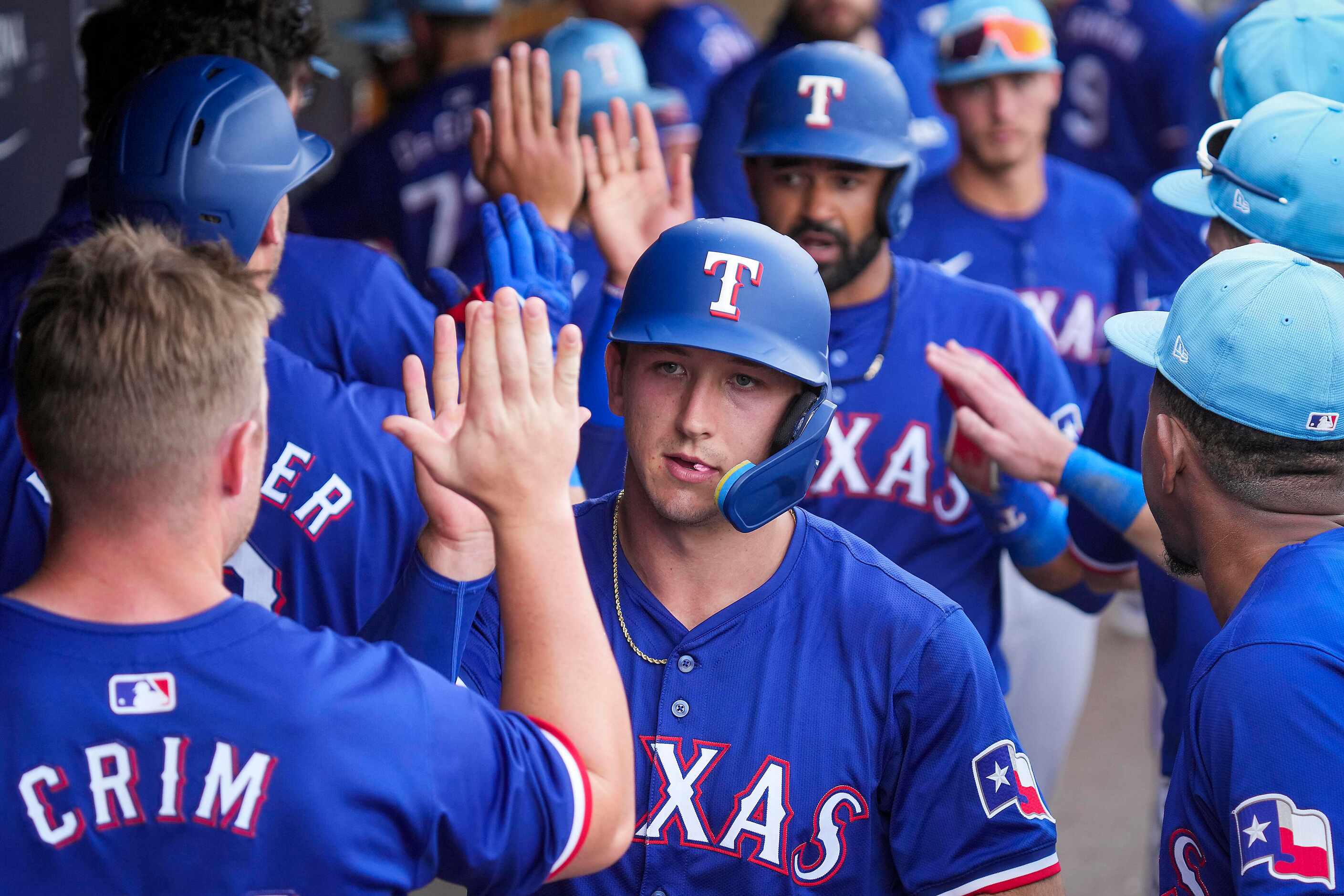 Texas Rangers outfielder Wyatt Langford celebrates in the dugout after scoring during the...