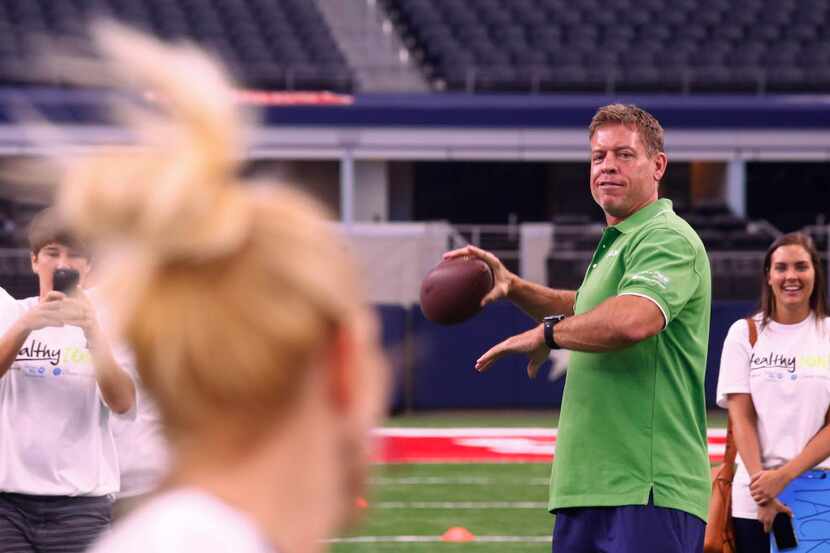 Former Dallas Cowboy Troy Aikman throws the ball to Amy Holderman, principal of Bennett...