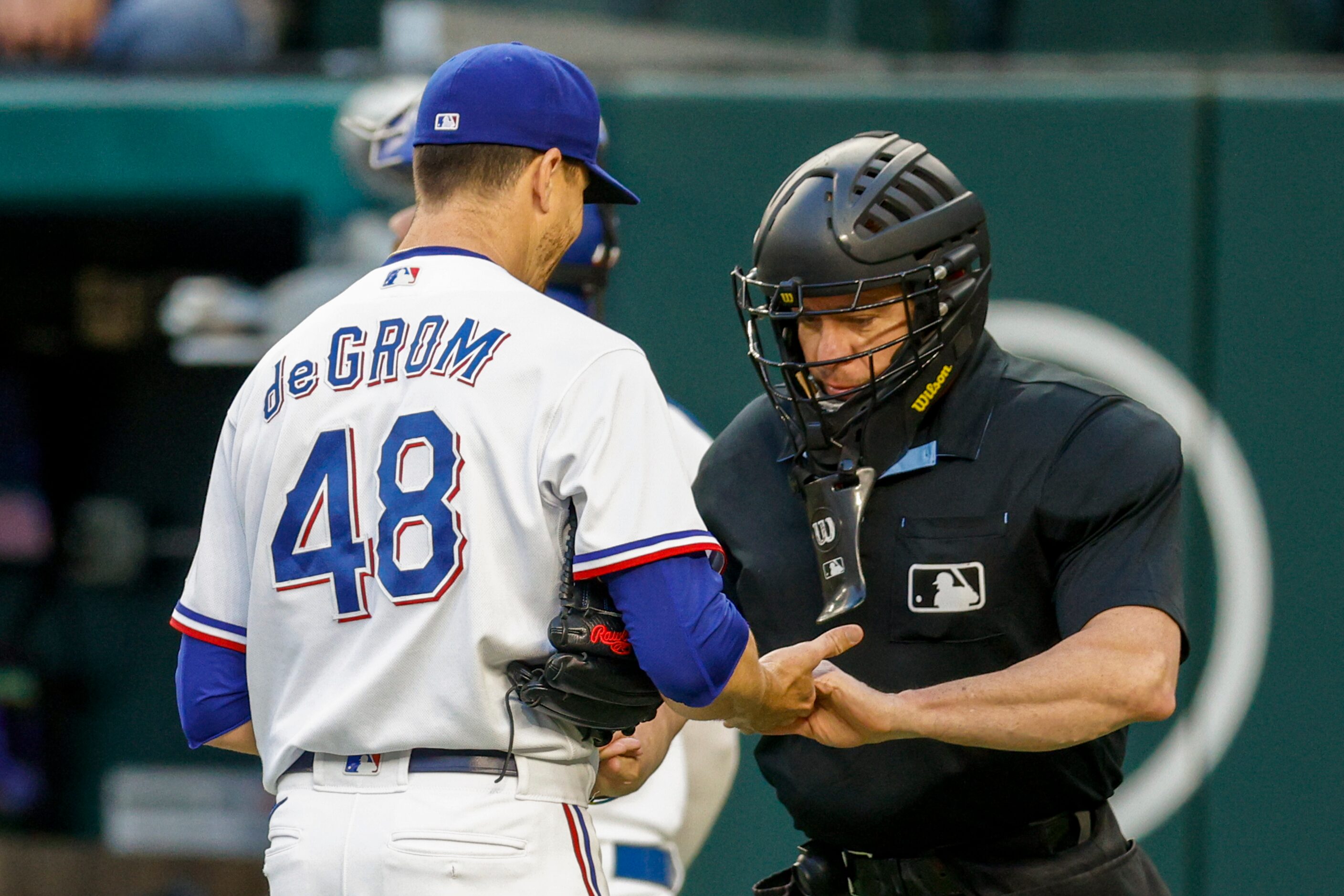 Umpire Carlos Torres (37) checks the hands of Texas Rangers starting pitcher Jacob deGrom...