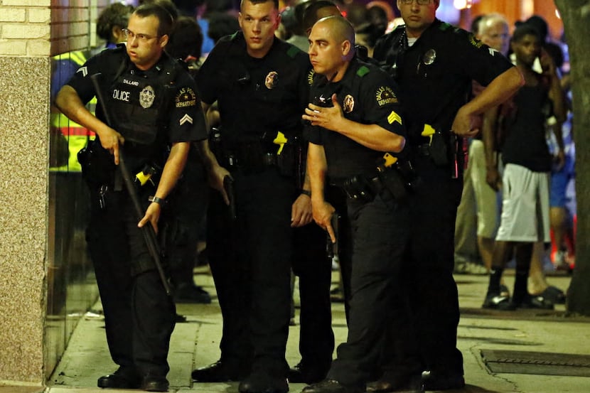 Police officers run with guns drawn into a parking garage during the deadly shooting Friday,...