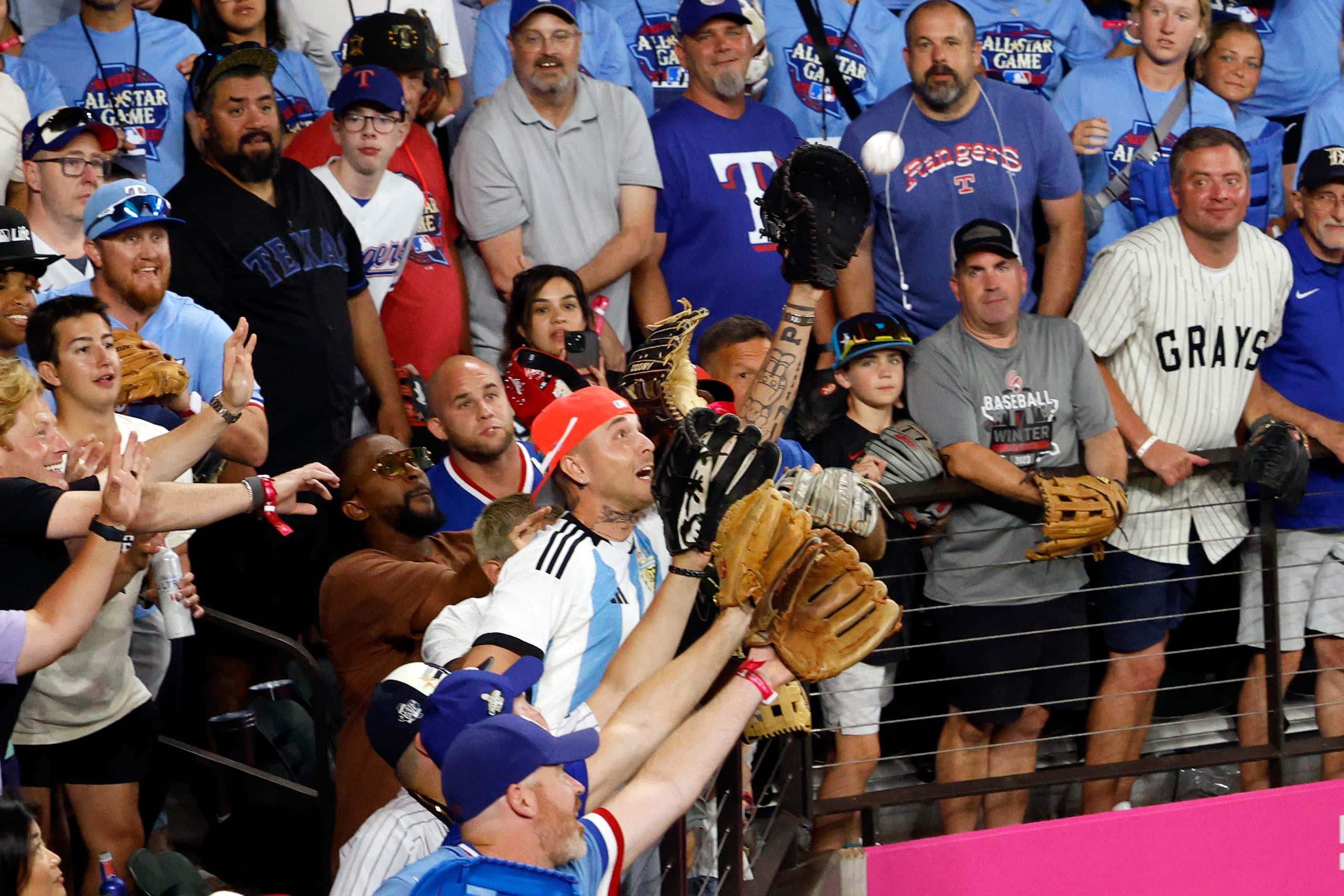 Fans reach out with gloves to try and catch a home run ball off the bat of American League's...