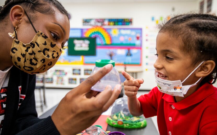 Prekindergarten assistant teacher Alexis Alexander shows Prosper Gilkey a closeup view of a...