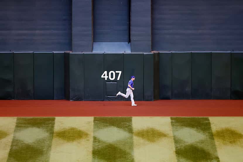 Texas Rangers starting pitcher Max Scherzer  jogs along the warning track as the pregame...