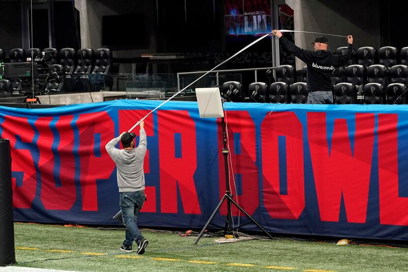 Workers use a tape measure as they hang a sign Jan. 29 inside Mercedes-Benz Stadium for...