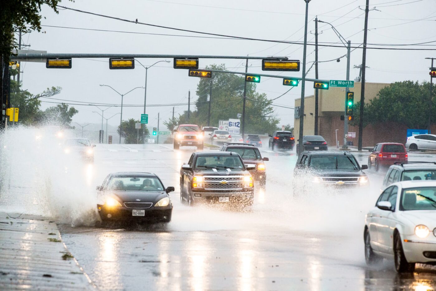 Cars drive through standing water at North Hampton Road in Dallas on Oct. 13, 2018.