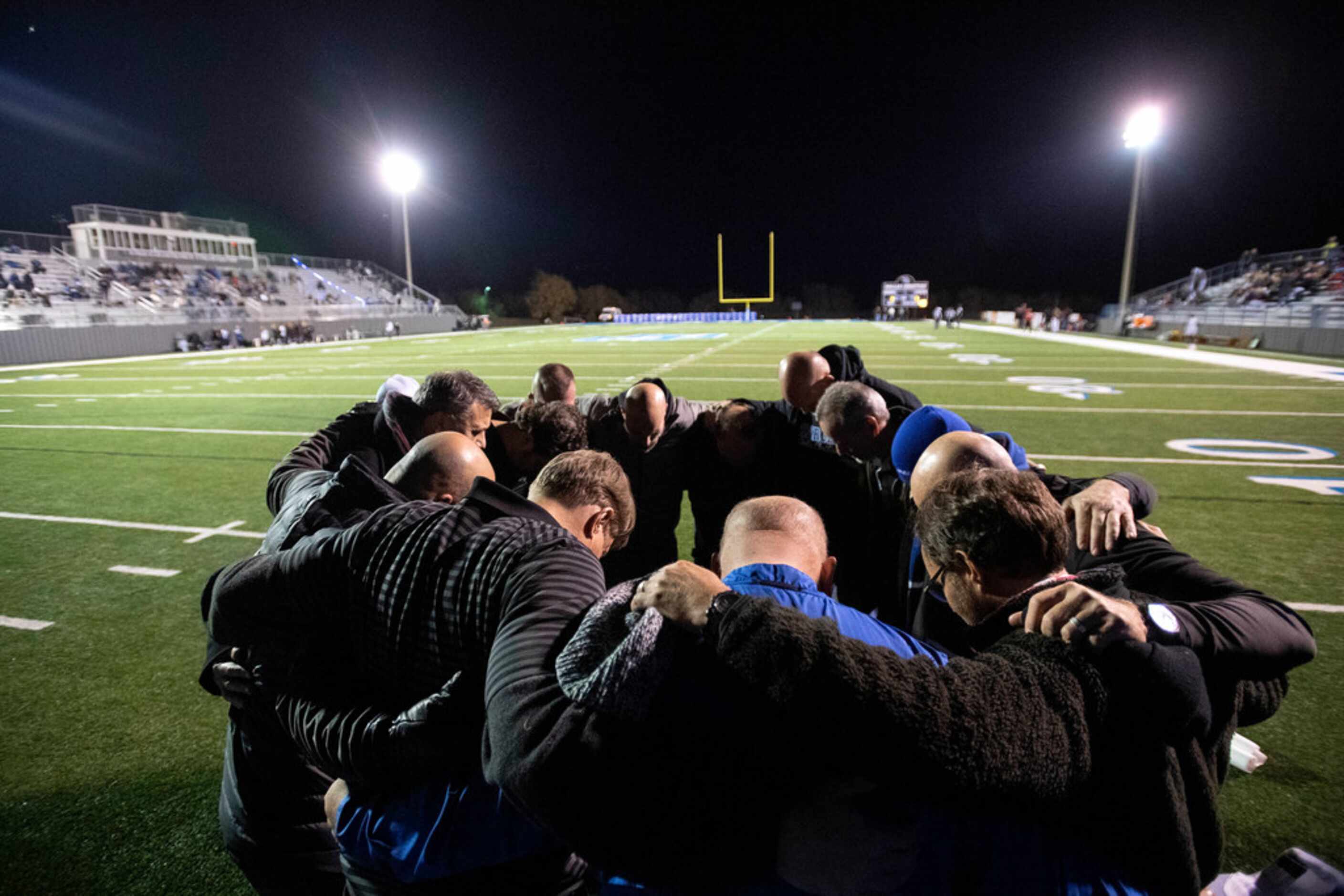 Dallas Christian dads pray before a high school football playoff game against Fort Worth...