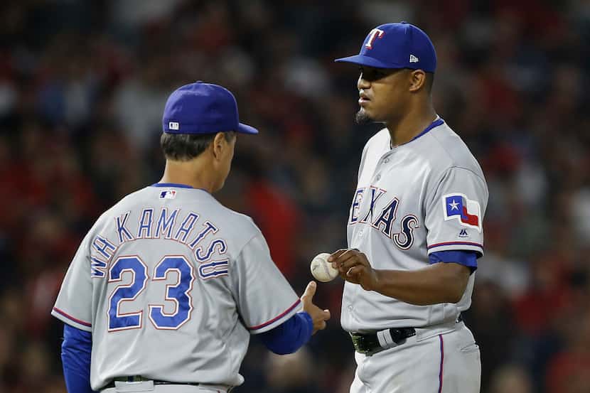 Texas Rangers starting pitcher Yohander Mendez, right, hands the ball to interim manager Don...