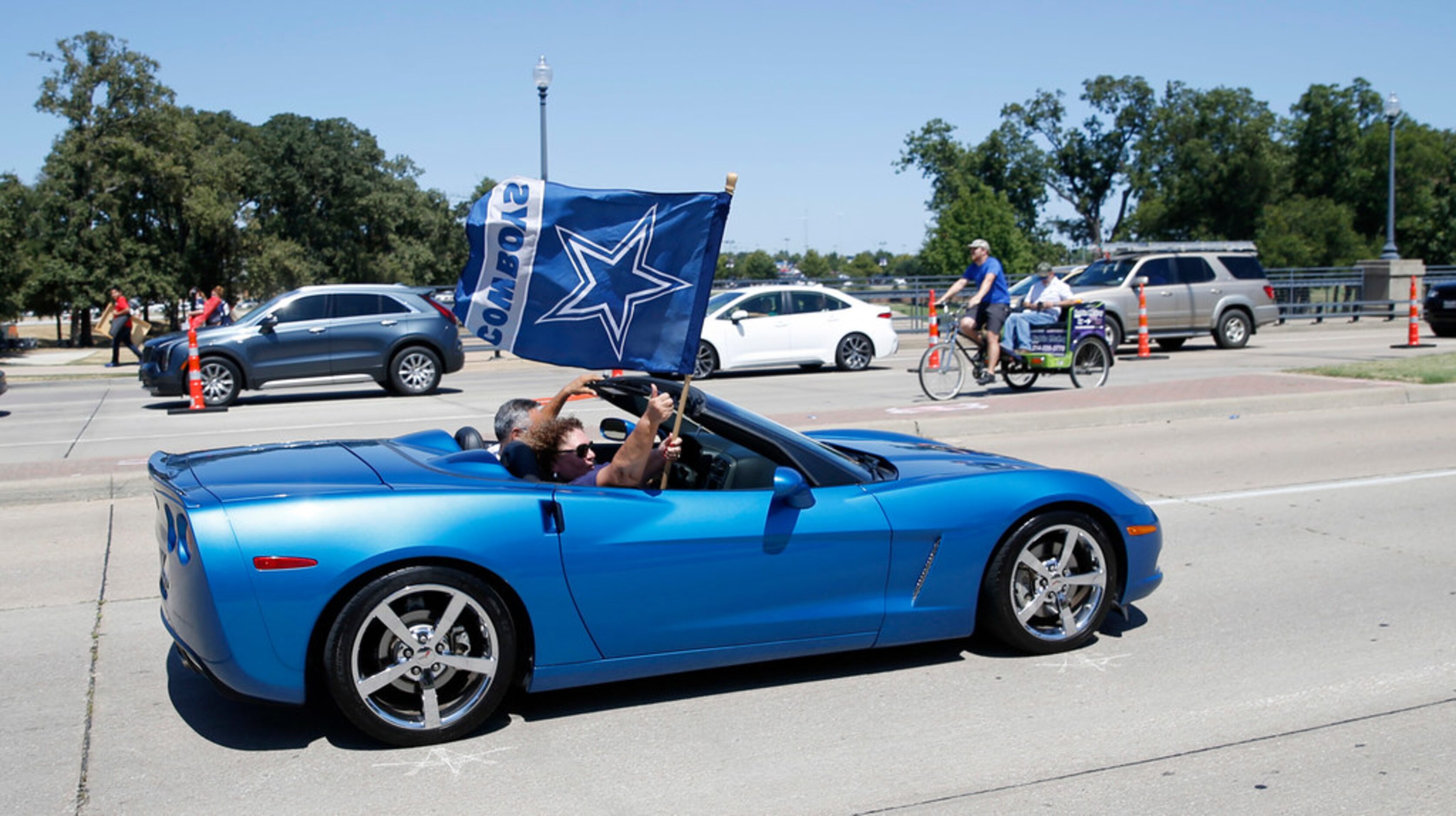 Dallas Cowboys fans wave a flag as they drive down the street before the home opener between...