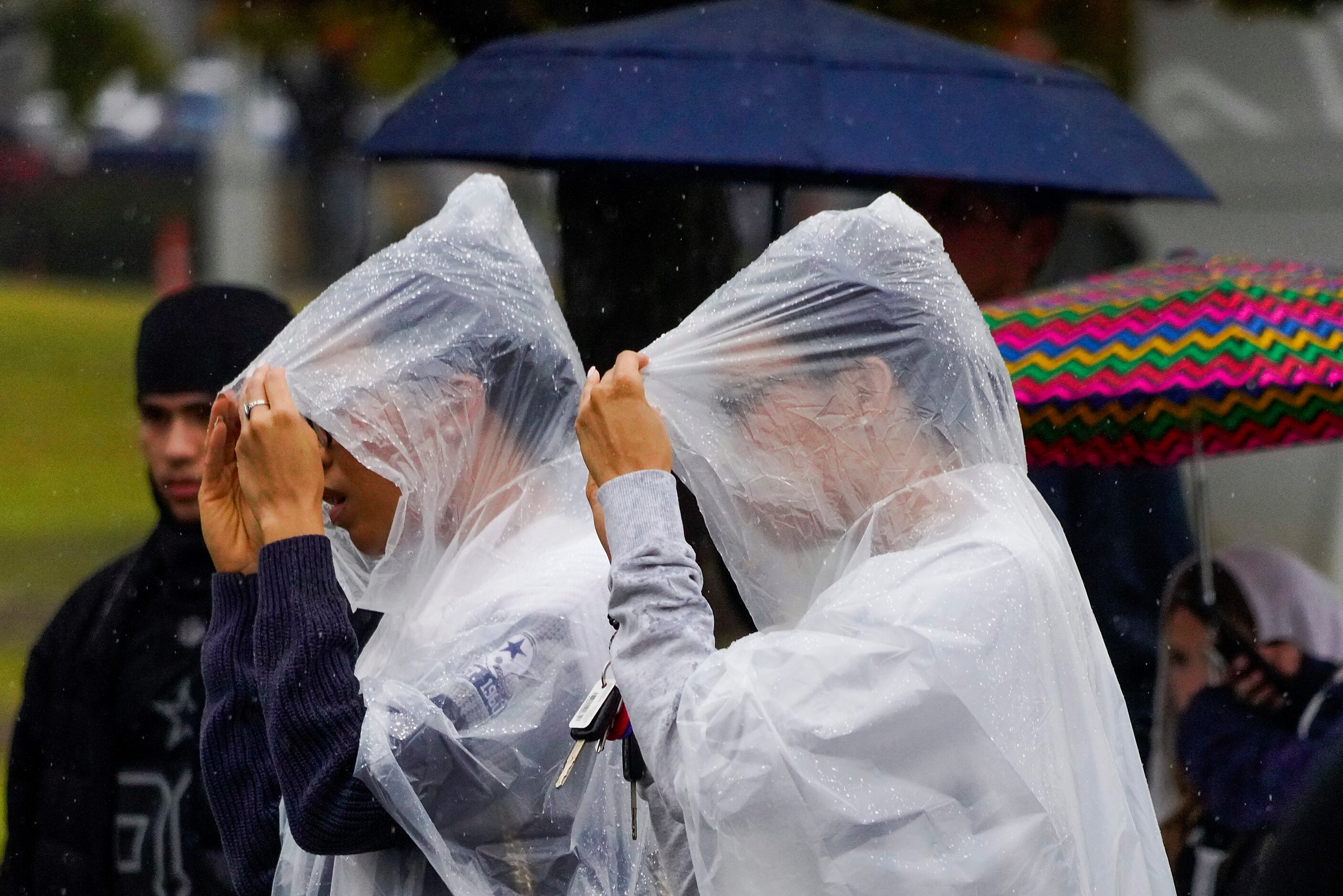 Fans head to the stadium in the rain before an NFL football game between the Dallas Cowboys...