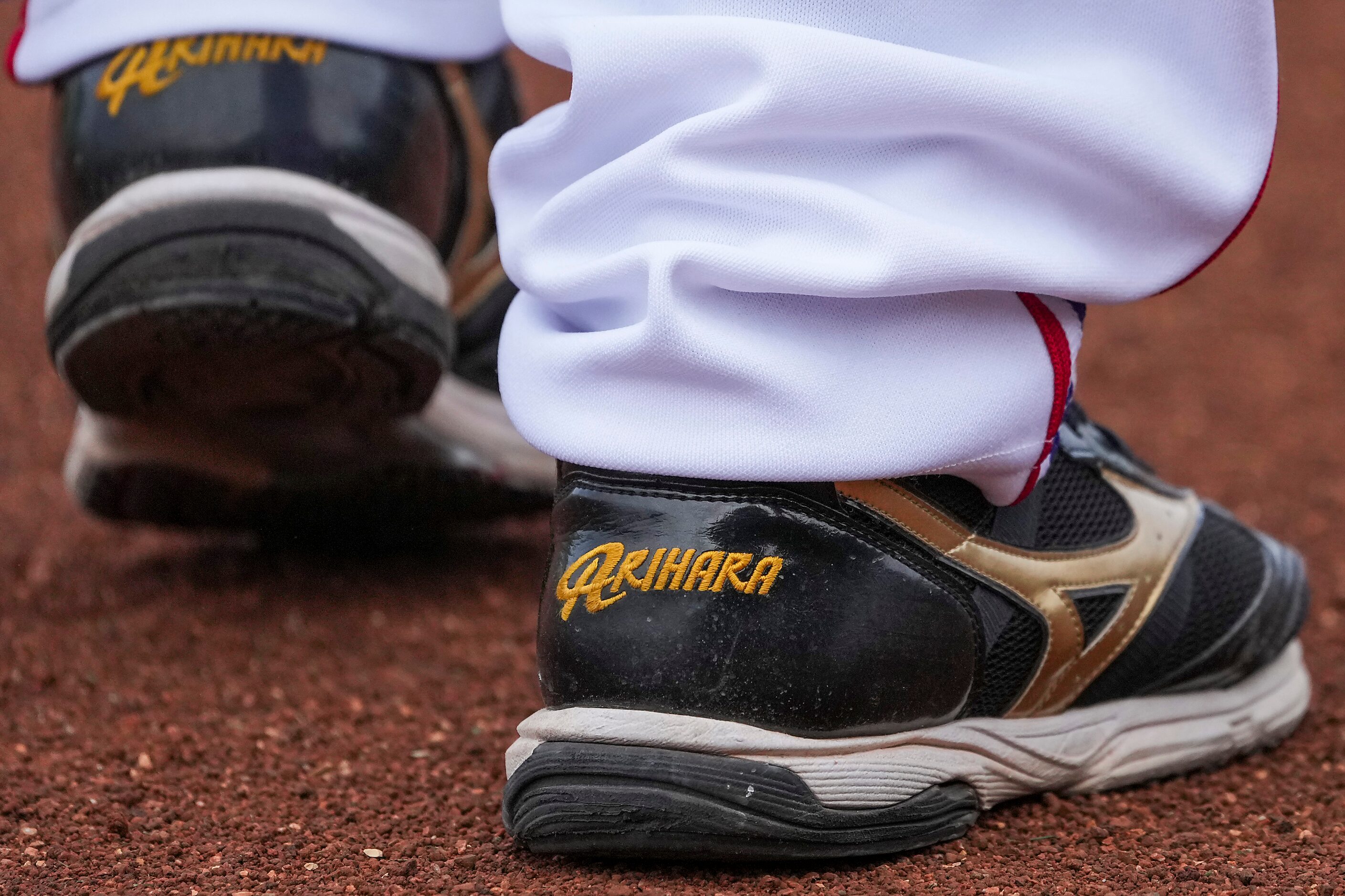 Texas Rangers pitcher Kohei Arihara walks on the warning track wearing his signature Mizuno...