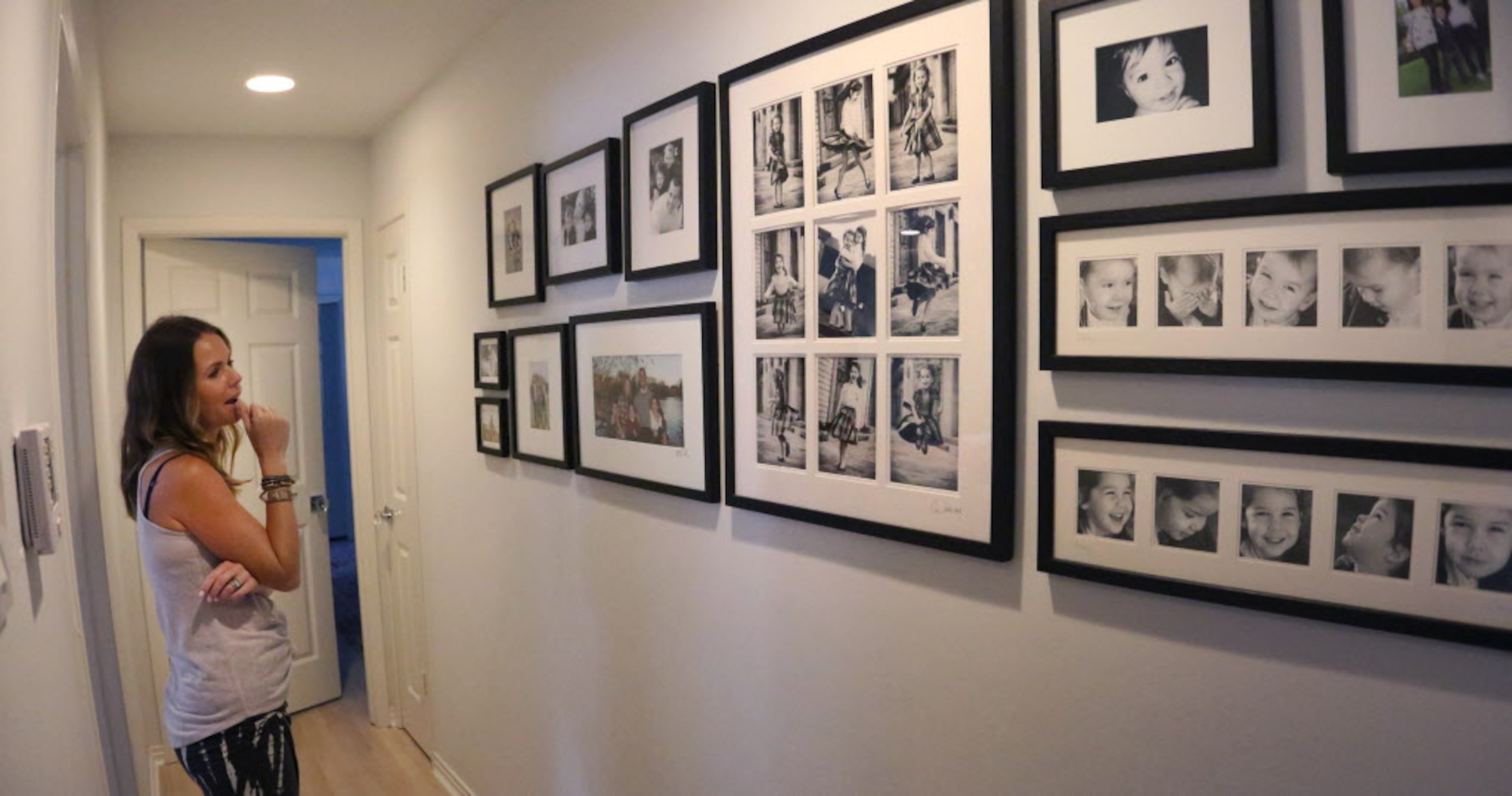 Kelly Turco looks at wall of photographs of their children at home in Dallas on Friday,...