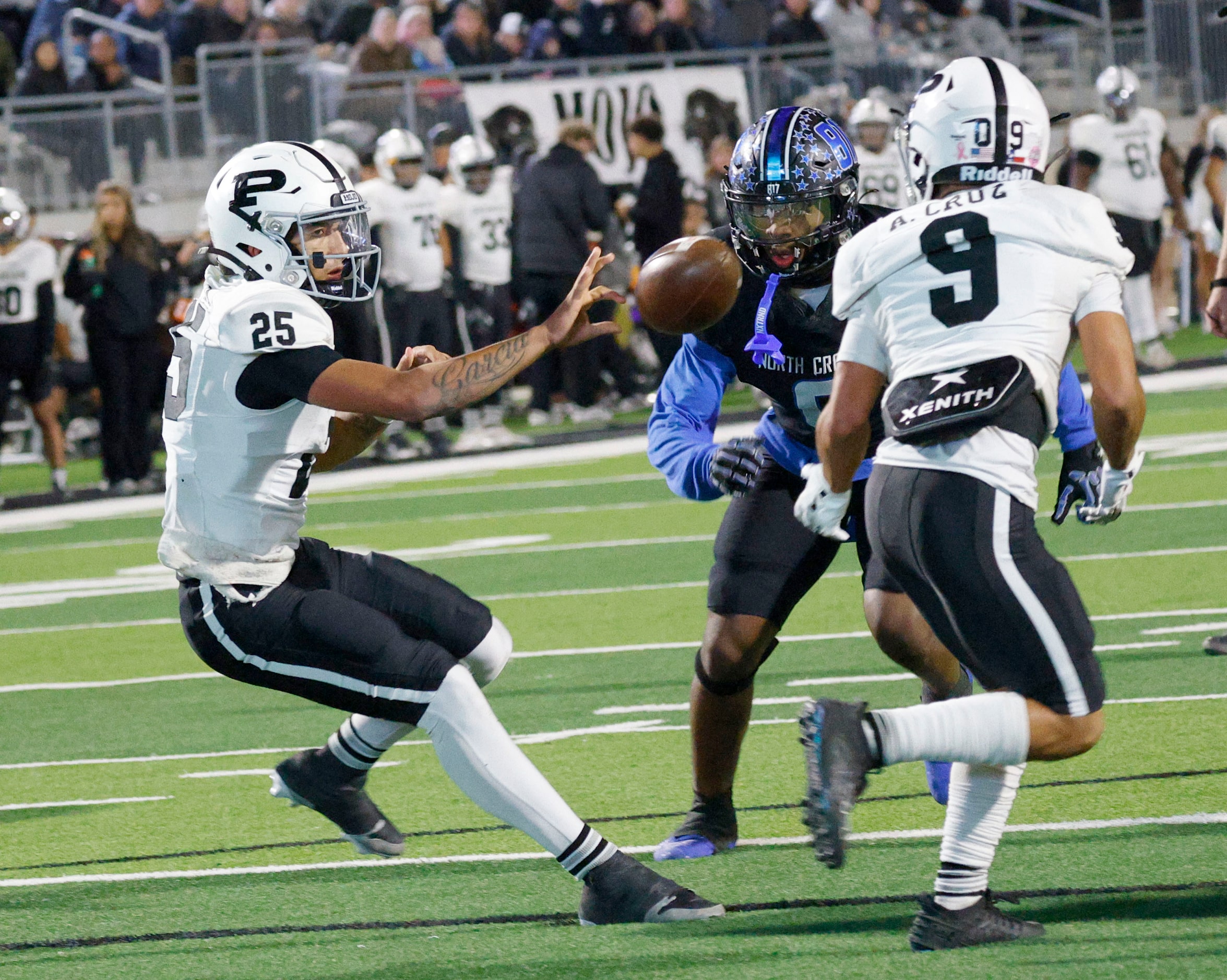 Permian's quarterback Jakob Garcia (25) hands off to Permian's Alexx Cruz (9) under pressure...