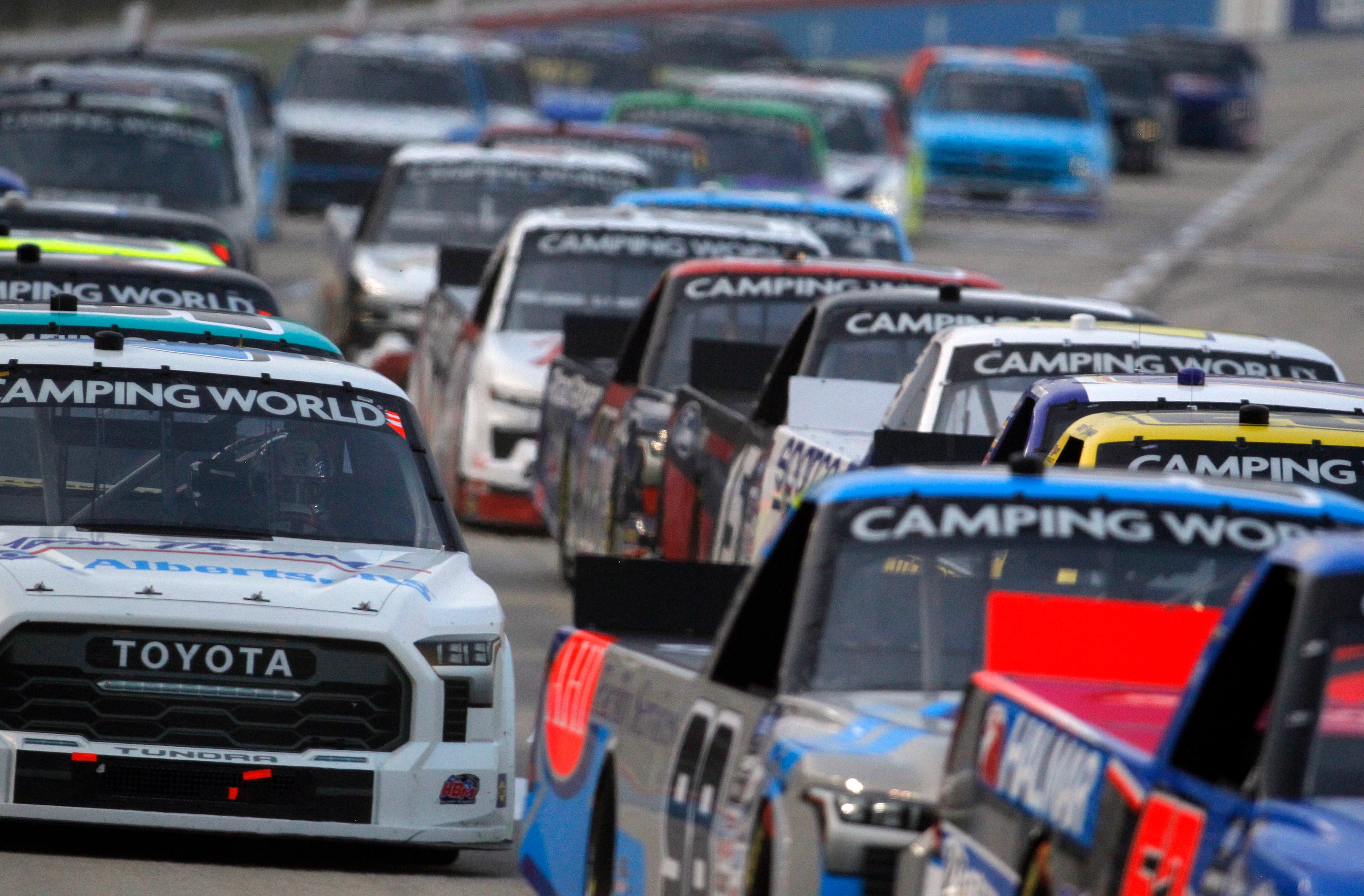 A compressed field of racers maneuver around the track at Texas Motor Speedway shortly after...