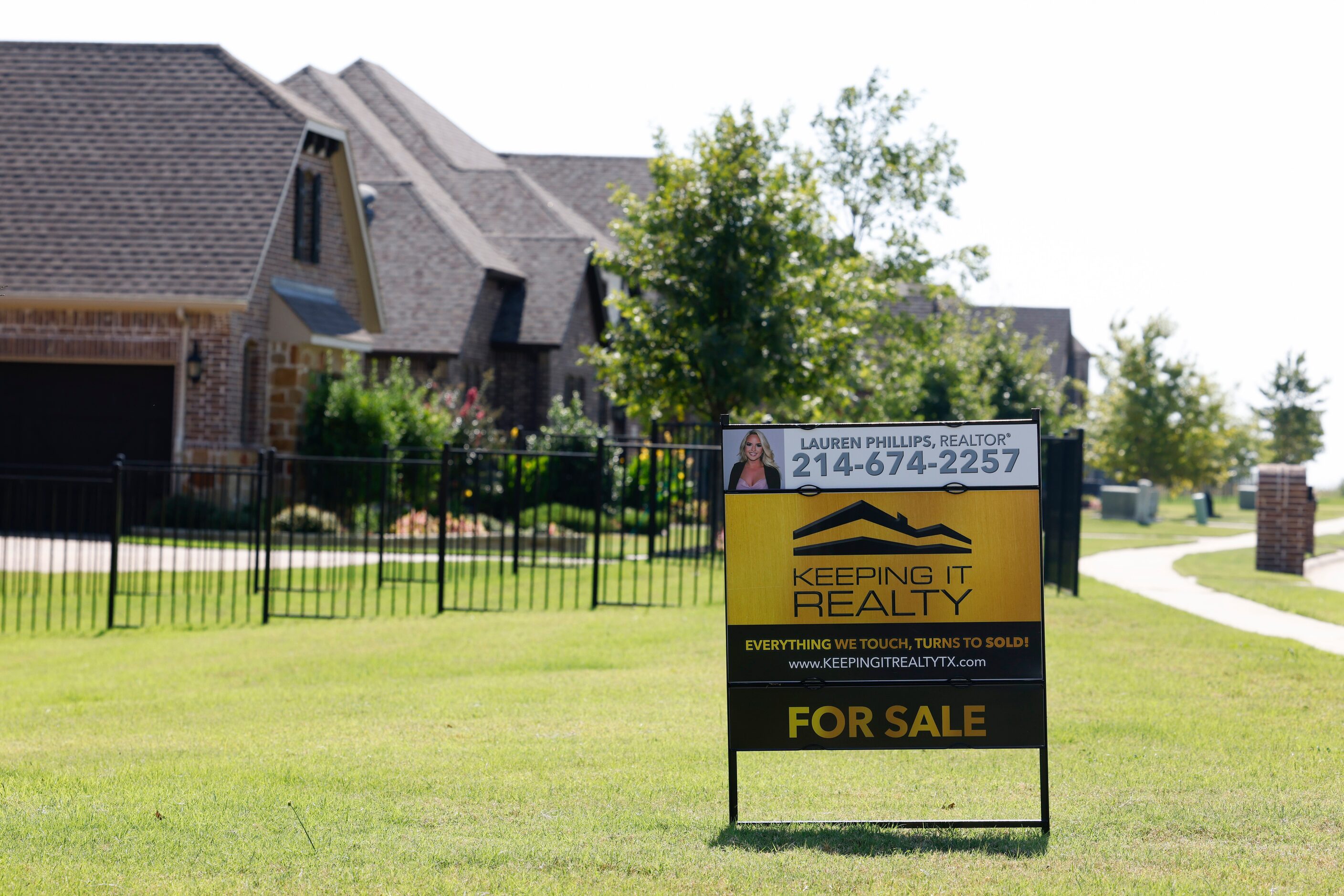 A For Sale sign displayed in front of a row of houses at the Bridges at Preston Crossing.