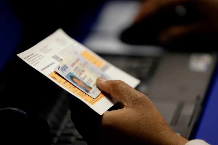 
An election official checks a voter’s photo identification at an early voting polling site...