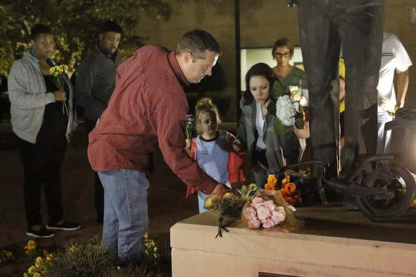  Trophy Club police Officer Keith Burris and his family place flowers Tuesday night at the...