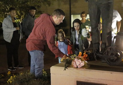  Trophy Club police Officer Keith Burris and his family place flowers Tuesday night at the...