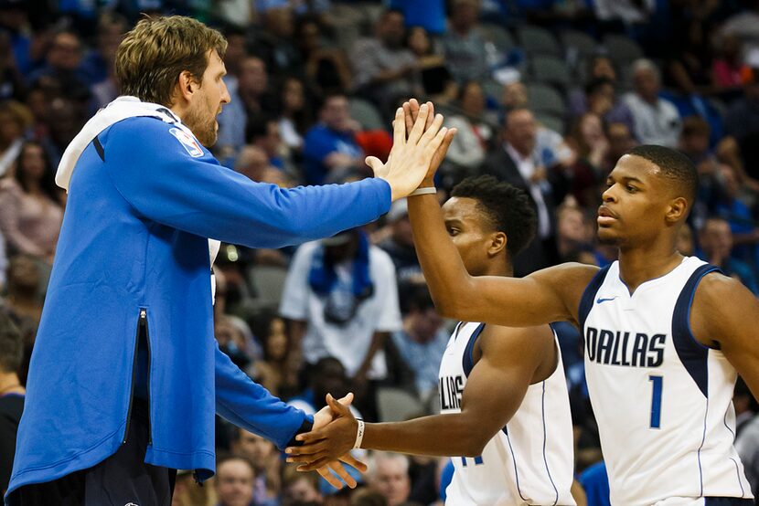 Dallas Mavericks guard Dennis Smith Jr. (1) gets a hand from forward Dirk Nowitzki as he...