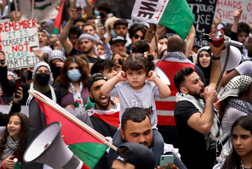 Surrounded by megaphones and chanting, a girl plugs her ears during the march through downtown.