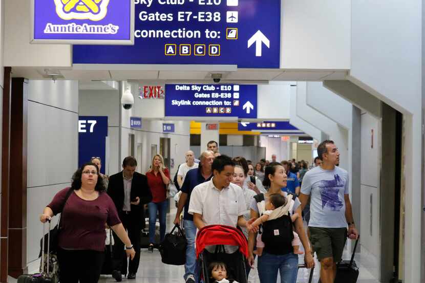 Travelers walk through Terminal E at Dallas Fort Worth International Airport. The airport...