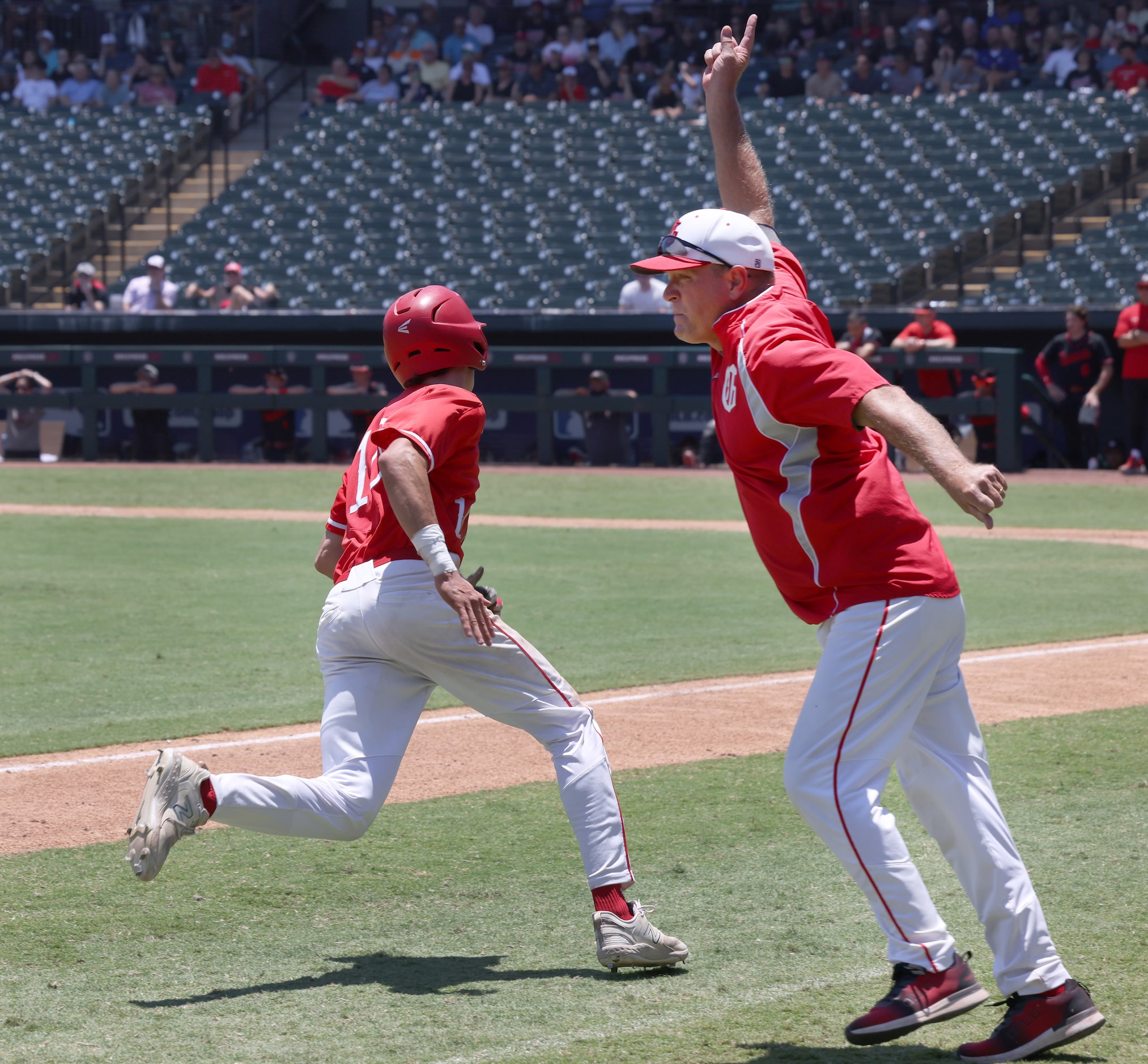 Grapevine head coach Jimmy Webster, right, sends base runner Sammy Kelley (10) to home plate...