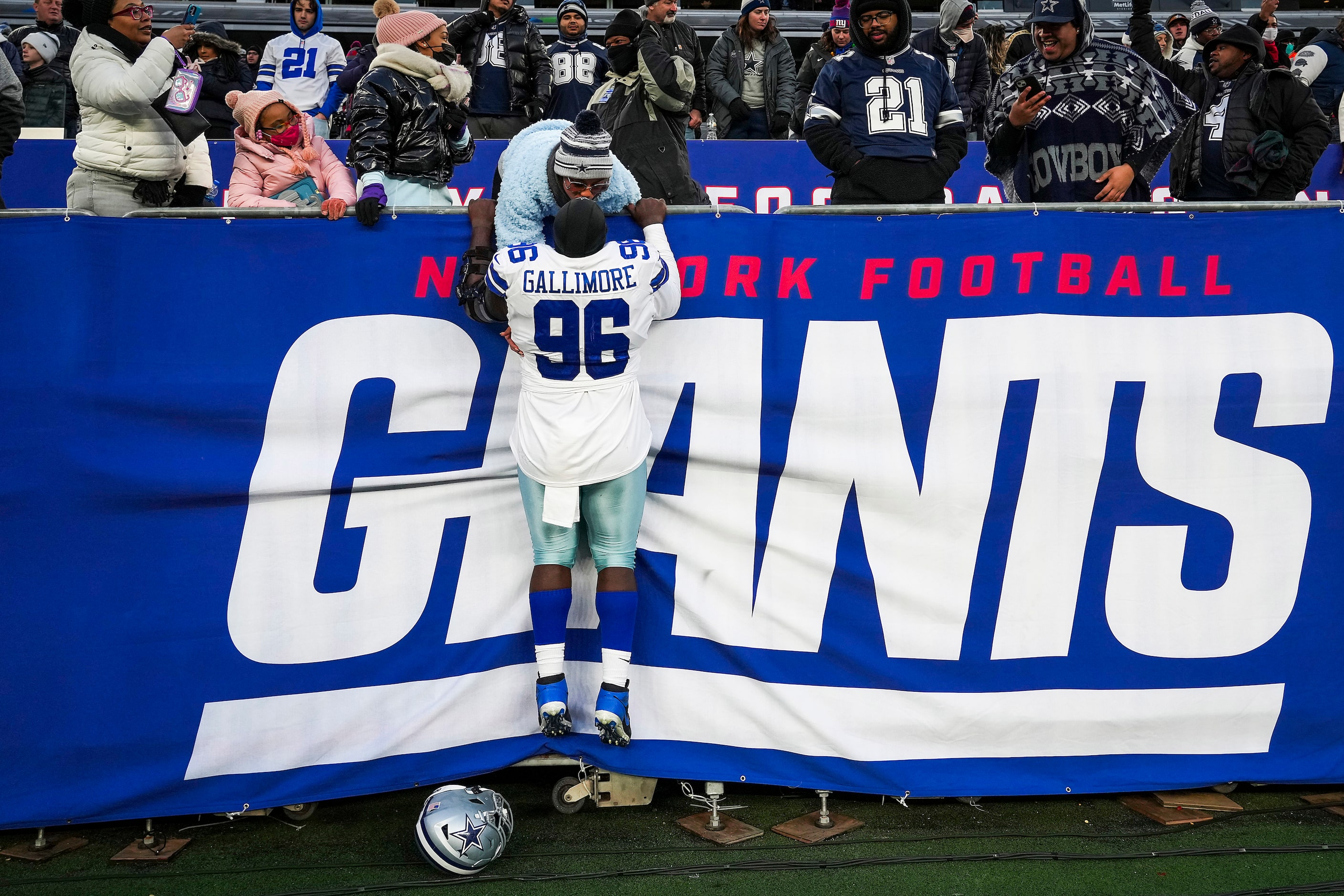 Dallas Cowboys defensive tackle Neville Gallimore (96) pulls himself up to the stands to get...