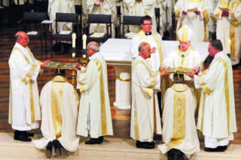  Bishop Kevin Farrell places the book of Gospel on the head of Monsignor Mark Seitz...